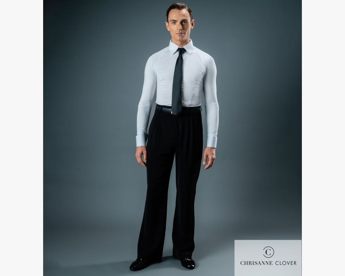Full-length studio portrait of a male ballroom dancer wearing black Chrisanne Clover practice trousers, a white long-sleeve dance shirt, and a black tie against a grey backdrop.