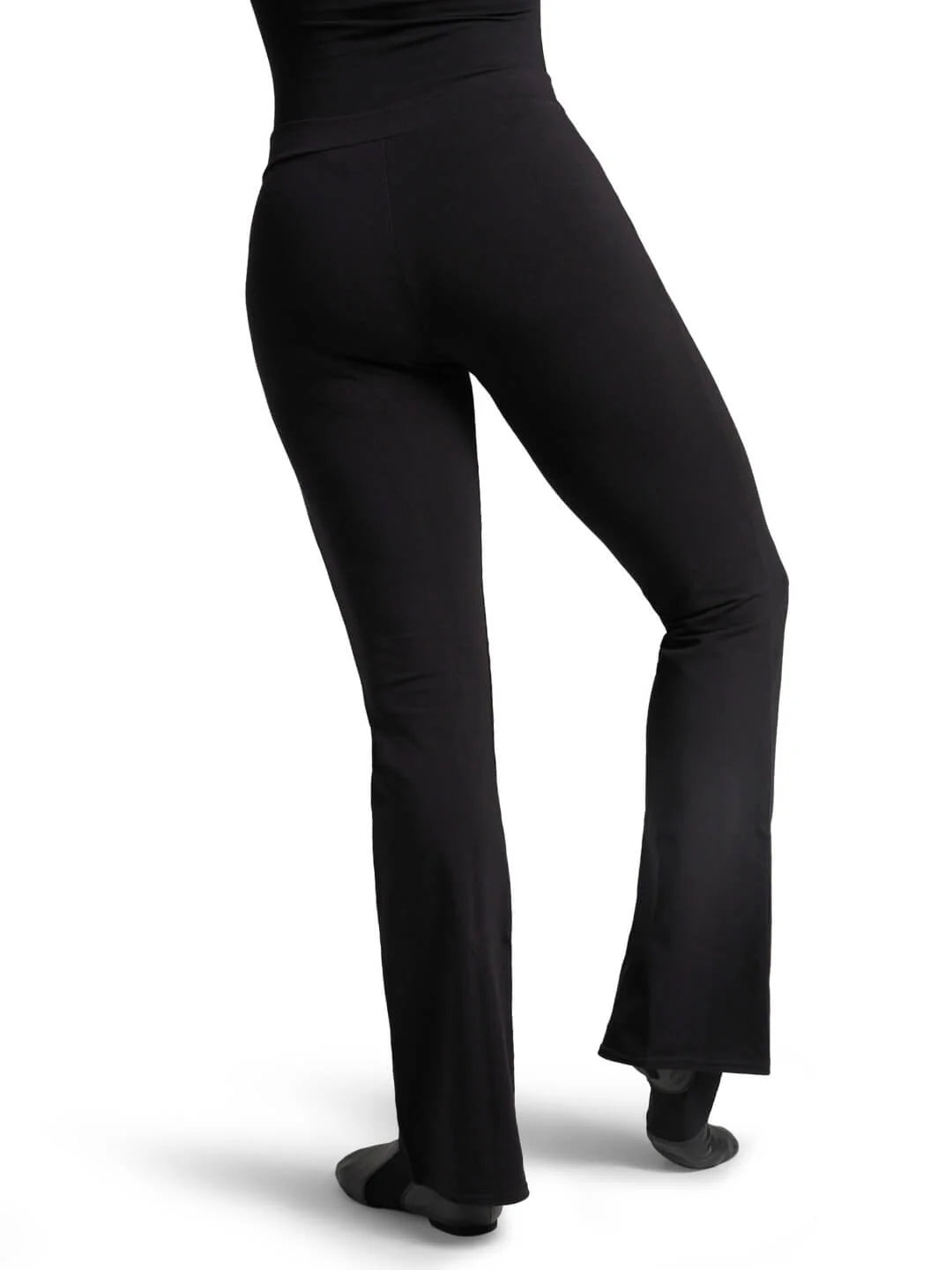 Back angle view of the black cotton Capezio® jazz pants, highlighting the seamless seat construction and elegant drape over dance shoes.