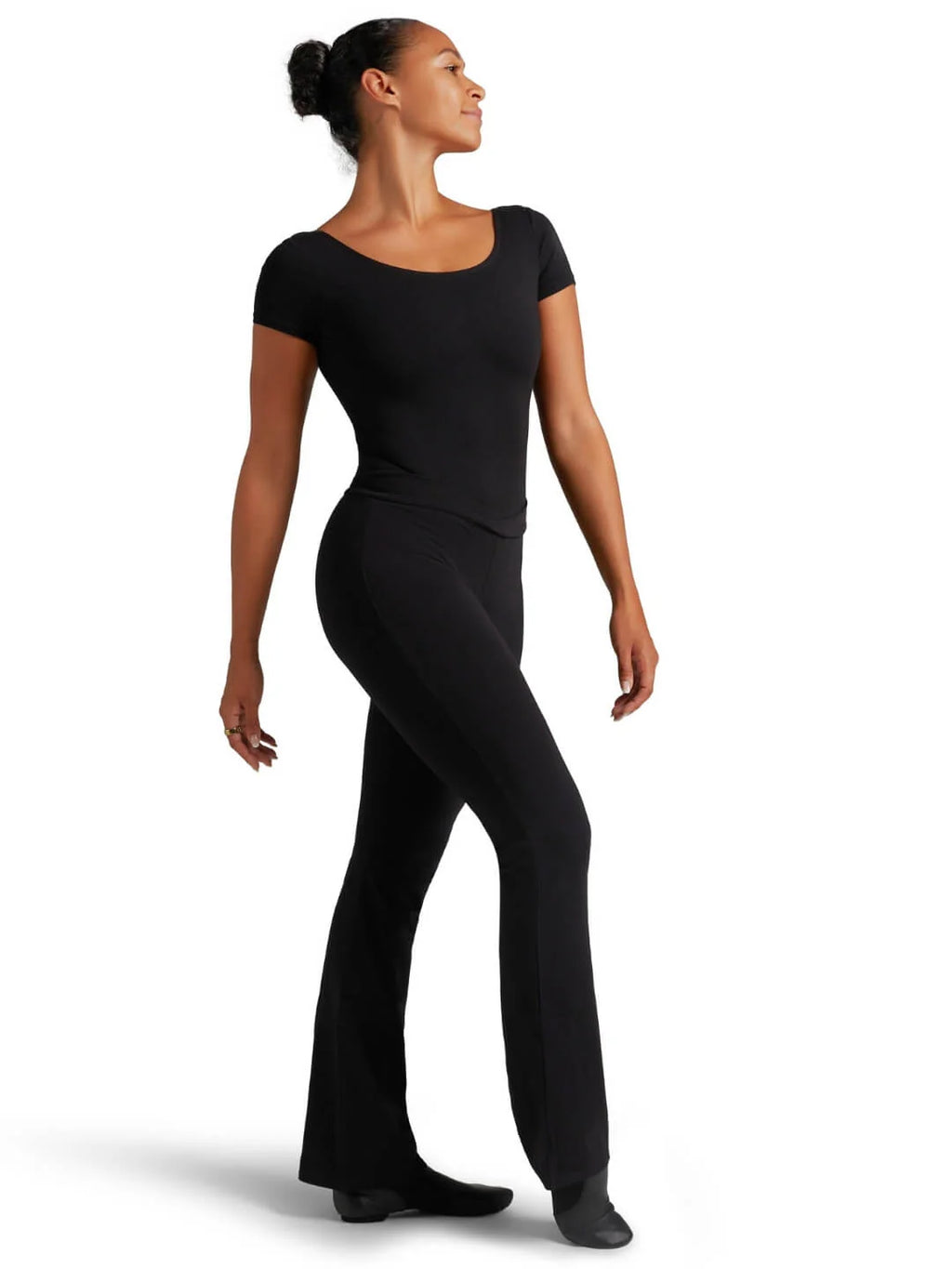 Full length studio shot of a female dancer posing in the black Capezio® V-front jazz pants and short sleeve top, highlighting full freedom of movement.