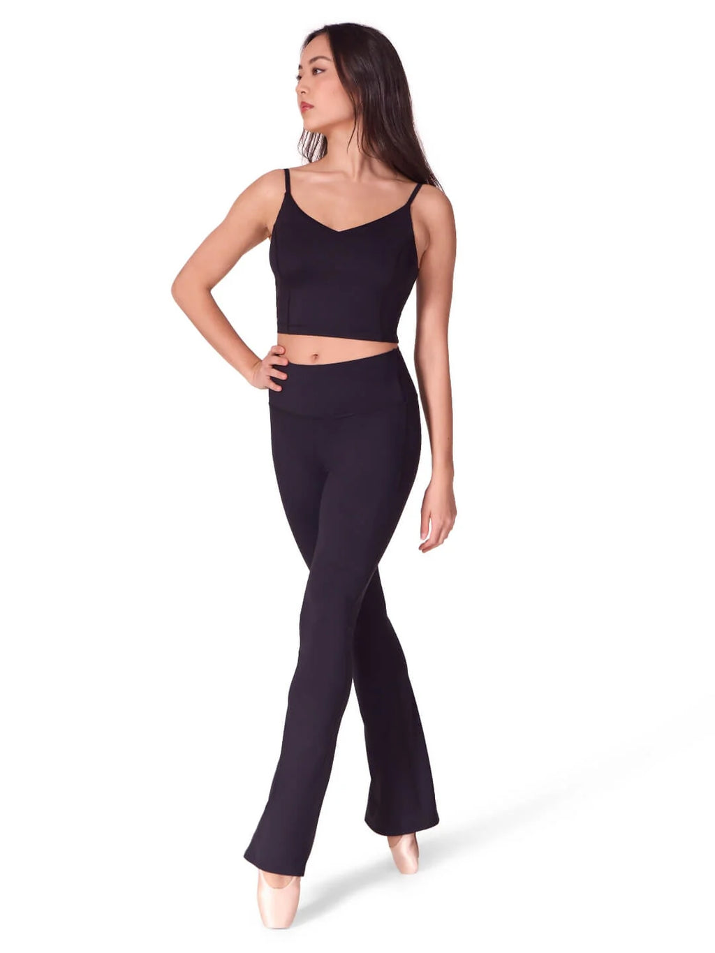 Full body studio shot of a model wearing the black Capezio® flare leggings and matching crop top, showcasing the complete professional activewear look.