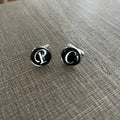 Pair of cufflinks with letter 'P' on a textured surface