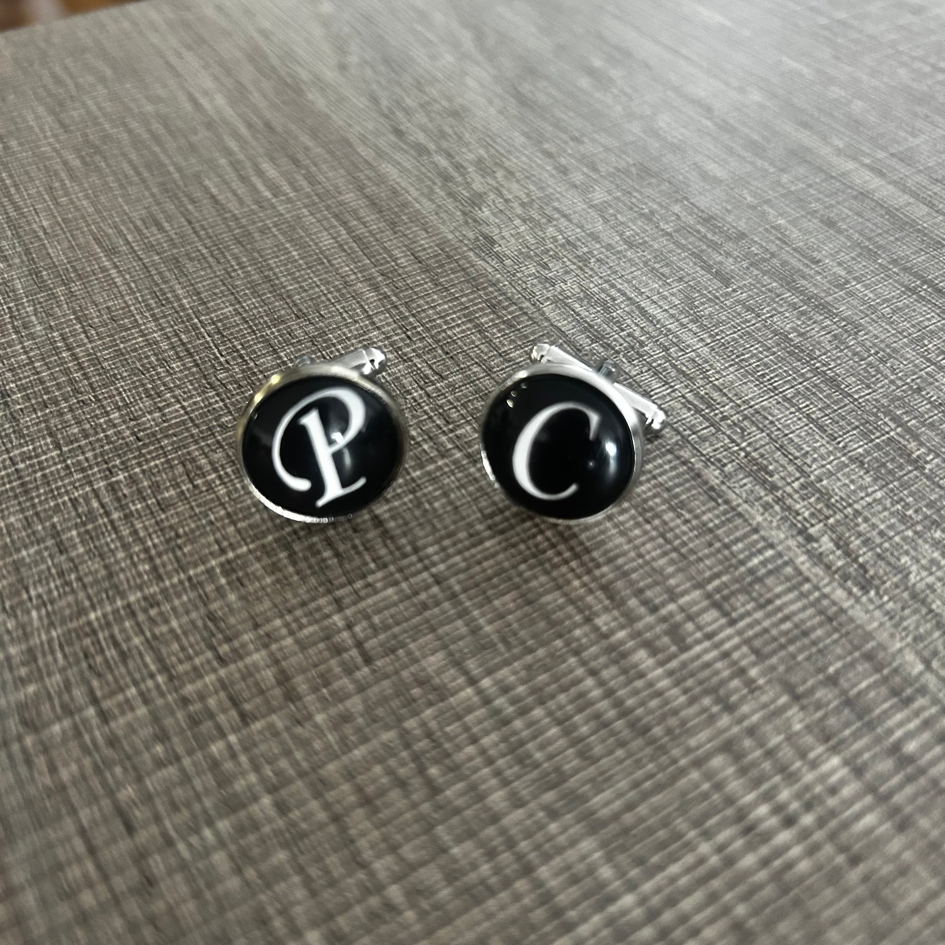 Pair of cufflinks with letter 'P' on a textured surface