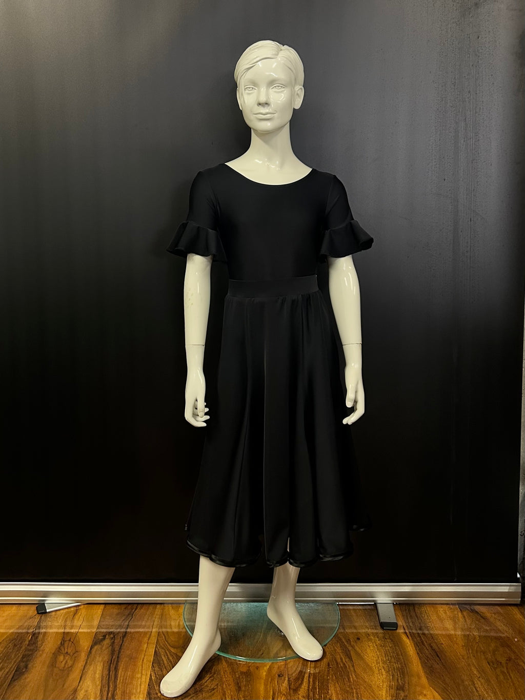Front view of the Ellie juvenile black matt Lycra 6-panel practice skirt with satin hemline on a studio mannequin.