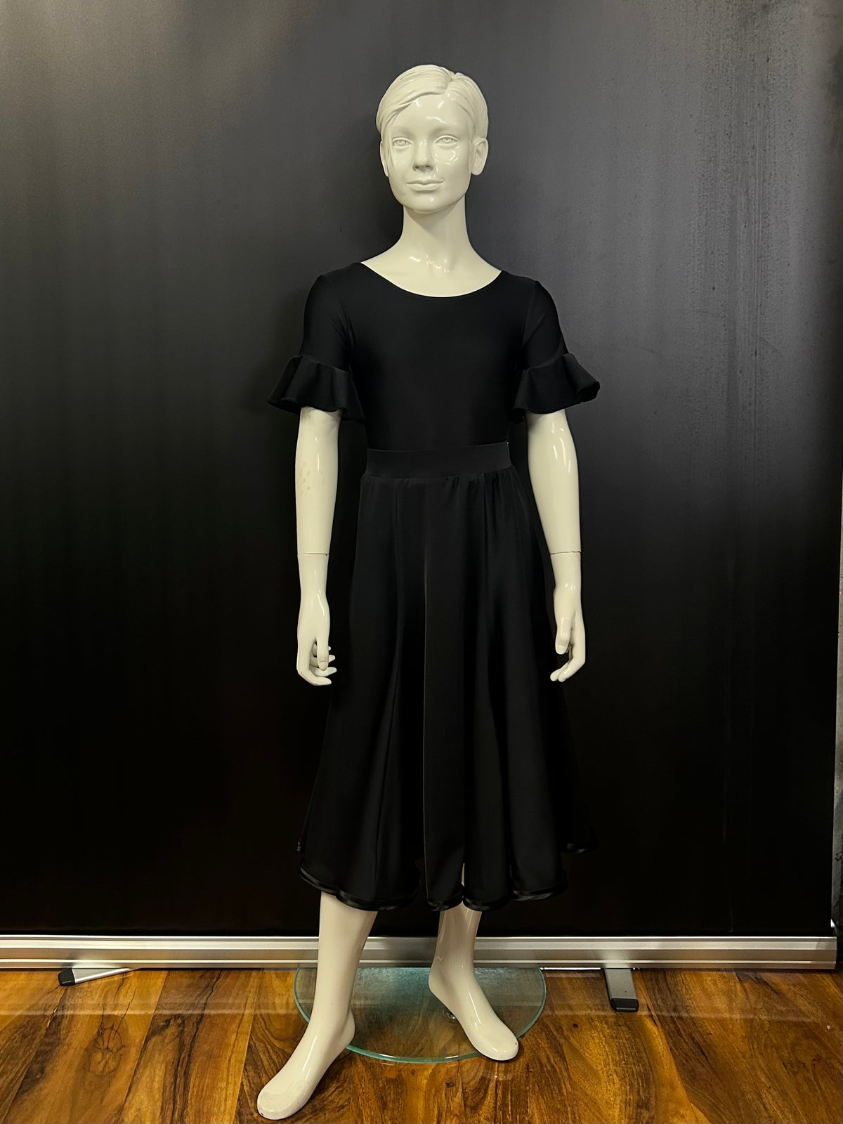 Front view of the Ellie juvenile black matt Lycra 6-panel practice skirt with satin hemline on a studio mannequin.