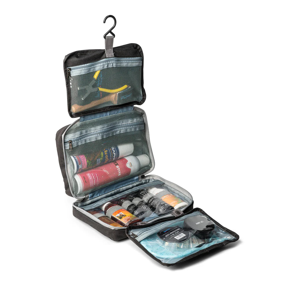 Black International Dance Shoes hanging Essentials Bag opened up to showcase four clear travel organizer compartments filled with dance cosmetics.