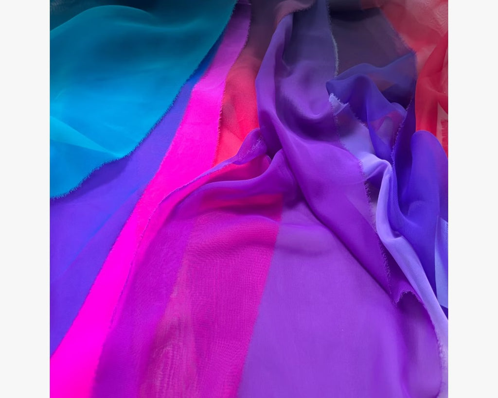 A draped display of vibrant Chrisanne Clover Luxury Georgette fabric in high-saturation Aqua and Orange, showcasing its fine matte texture and lightweight fluid movement.