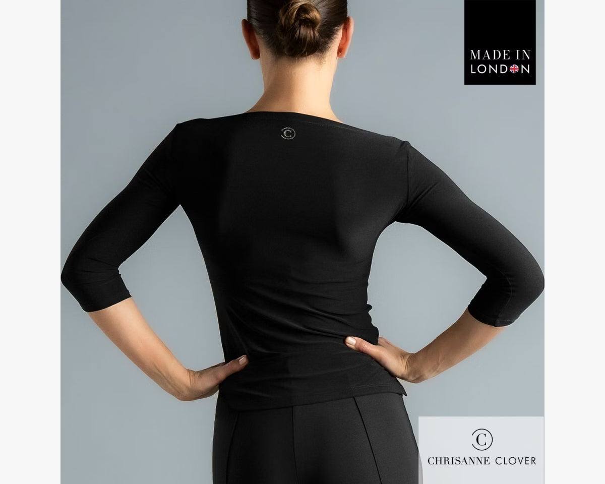 Rear view of a female model wearing the black Chrisanne Clover Eternity practice top, highlighting the small circular metallic logo detail at the center back neckline.