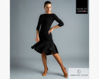 Full-length view of a female Latin dancer wearing the black Chrisanne Clover Eternity Top with a ruffled practice skirt, fishnets, and tan Latin dance shoes.